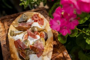 A7R07813 - 2023 - Gees Restaurant & Bar - Oxford - High Res - Artichoke Fig Prosciutto Pizzetta Sunlight Green Flowers - Web Hero